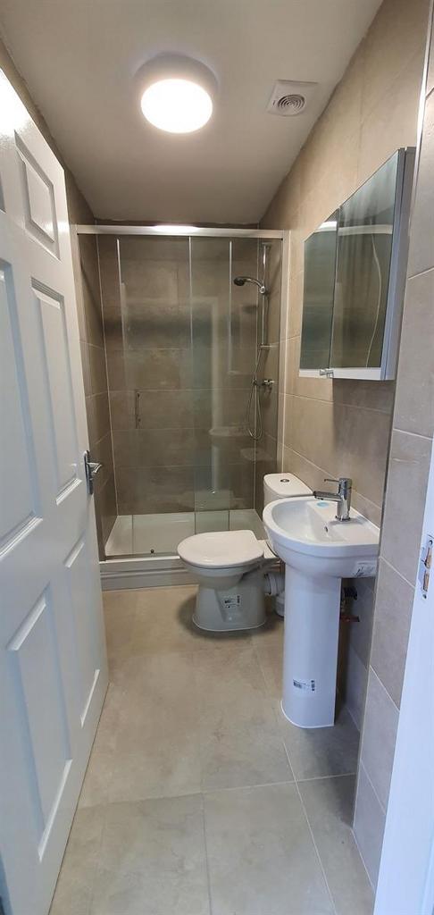 Modern tiled bathroom with a glass-enclosed sho...