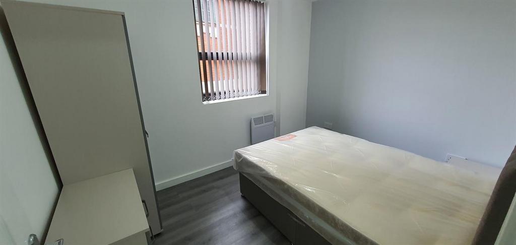 Compact, tidy bedroom with a bed, freestanding ...