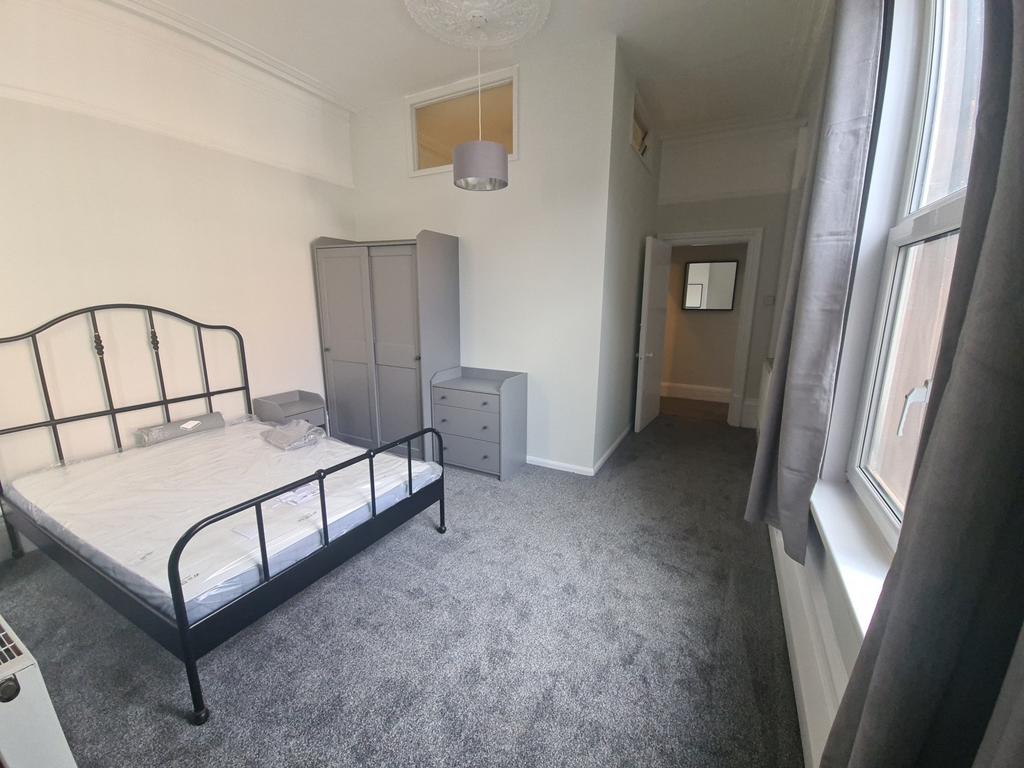 Bright double bedroom with large window and bed...