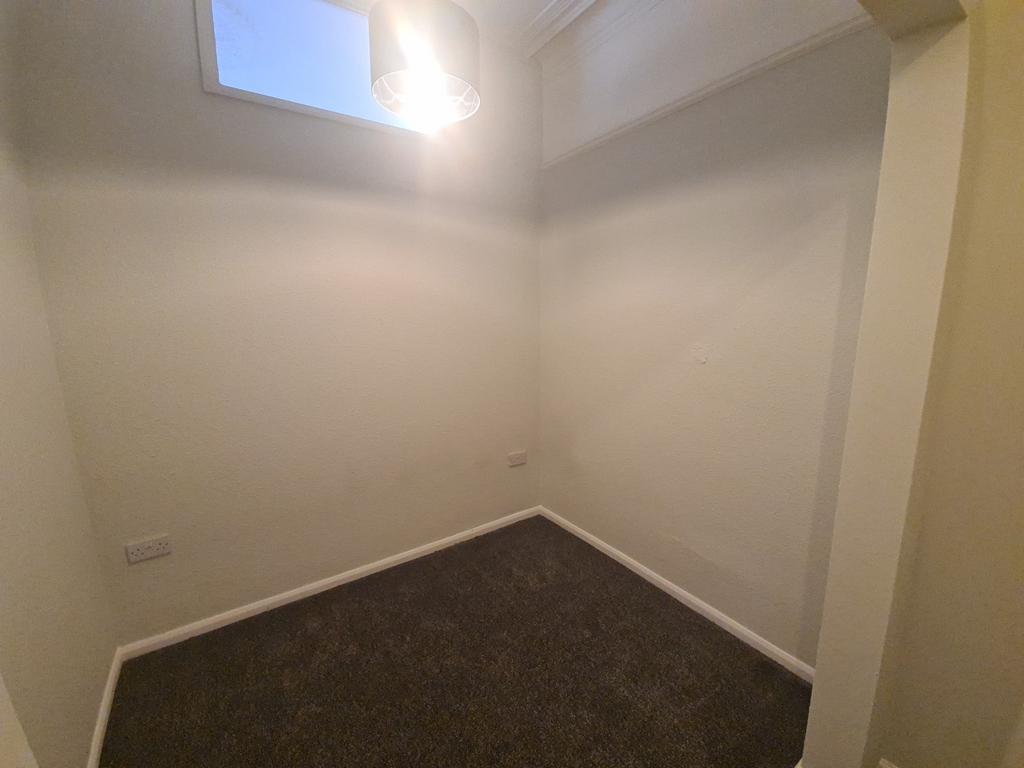 Small neutral room with high window and carpet...