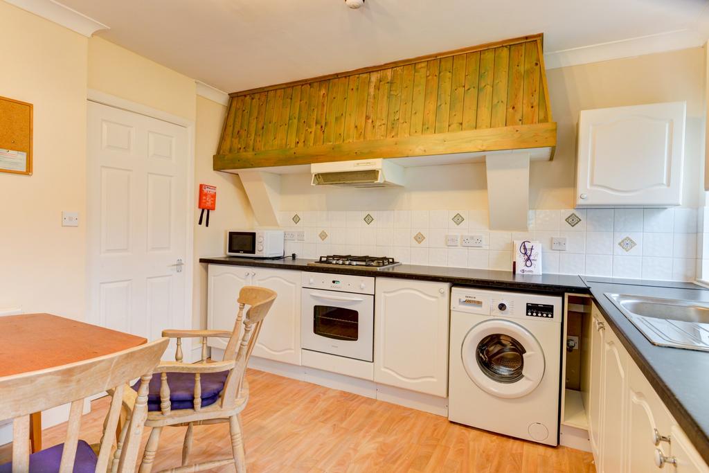 A well-lit kitchen featuring basic appliances a...