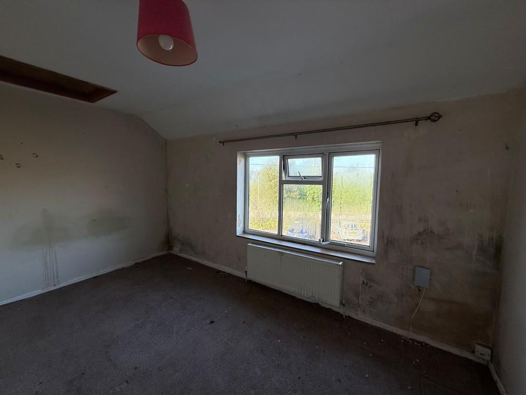 Main bedroom with slanted ceilings, window and rad