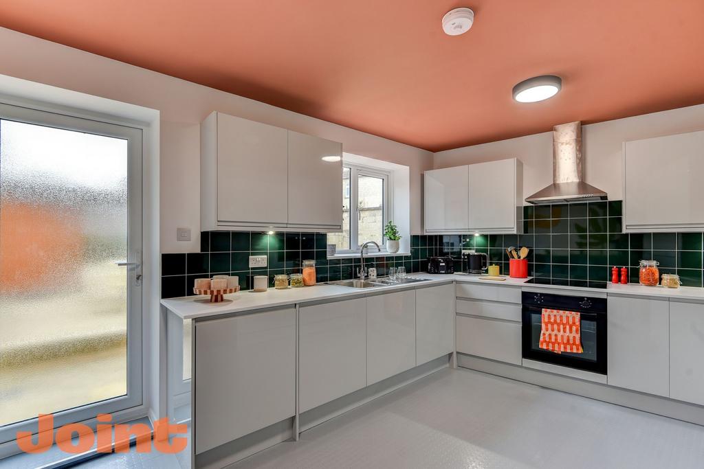 Contemporary L-shaped kitchen with glossy white...