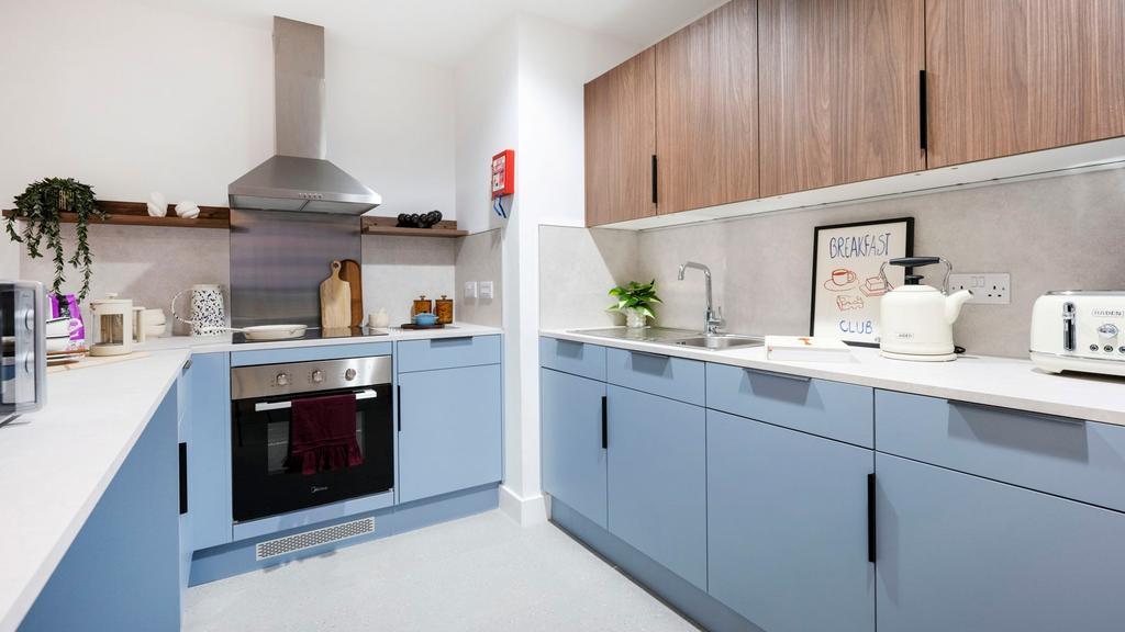 Modern fitted kitchen with pastel blue lower ca...