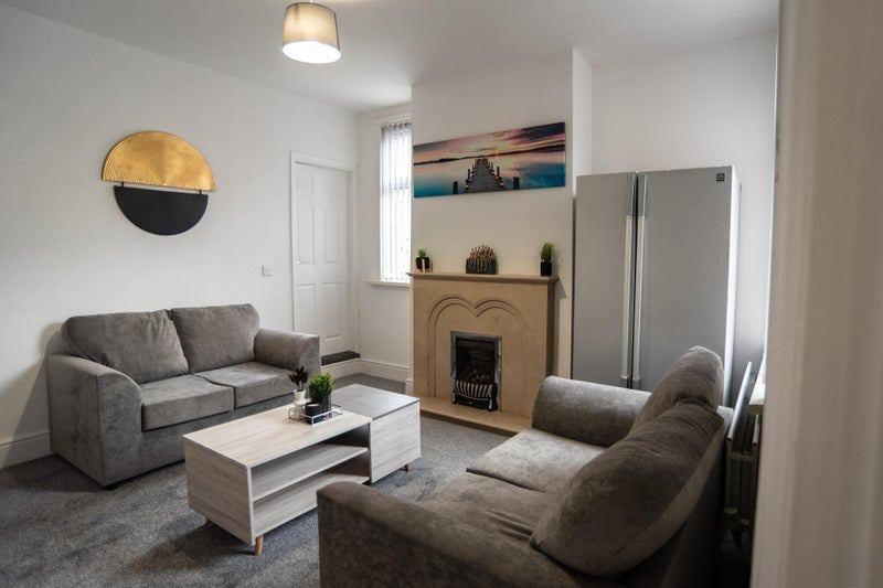 Bright, modern living room with matching grey s...