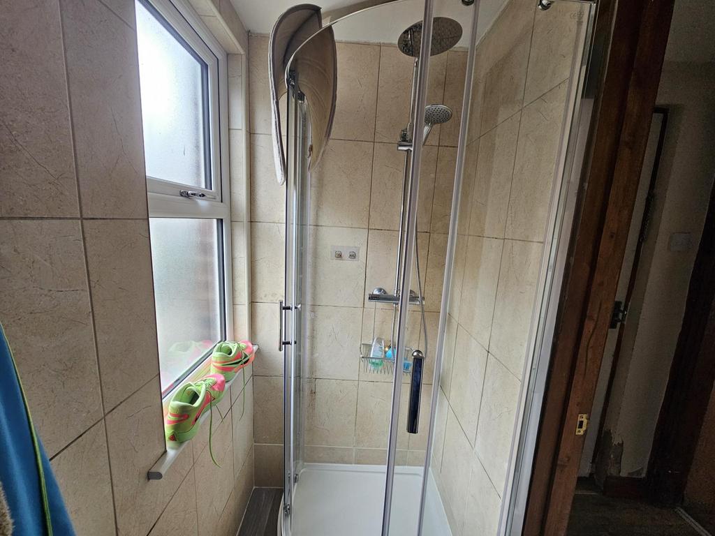 Bright tiled shower cubicle with rainfall head...