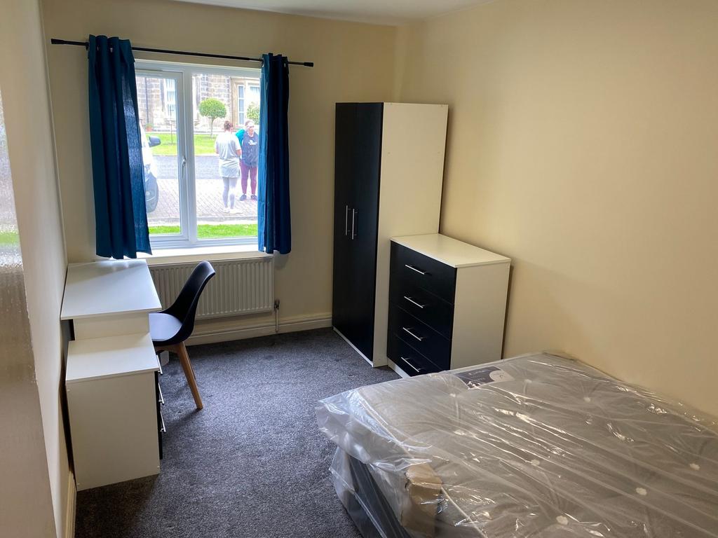 A well-lit, tidy single bedroom with a window p...