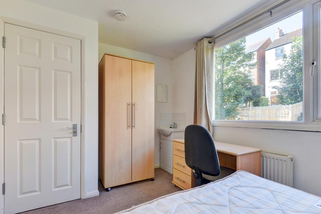 A bright and tidy student bedroom featuring a w...