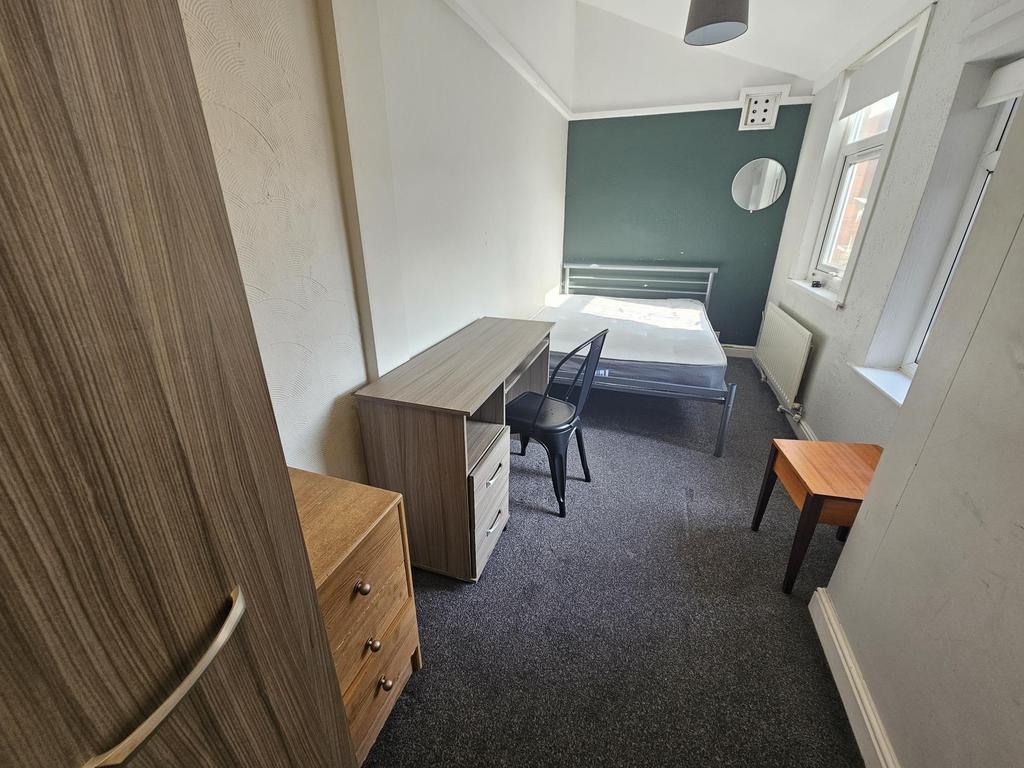Bright furnished bedroom with desk and storage...