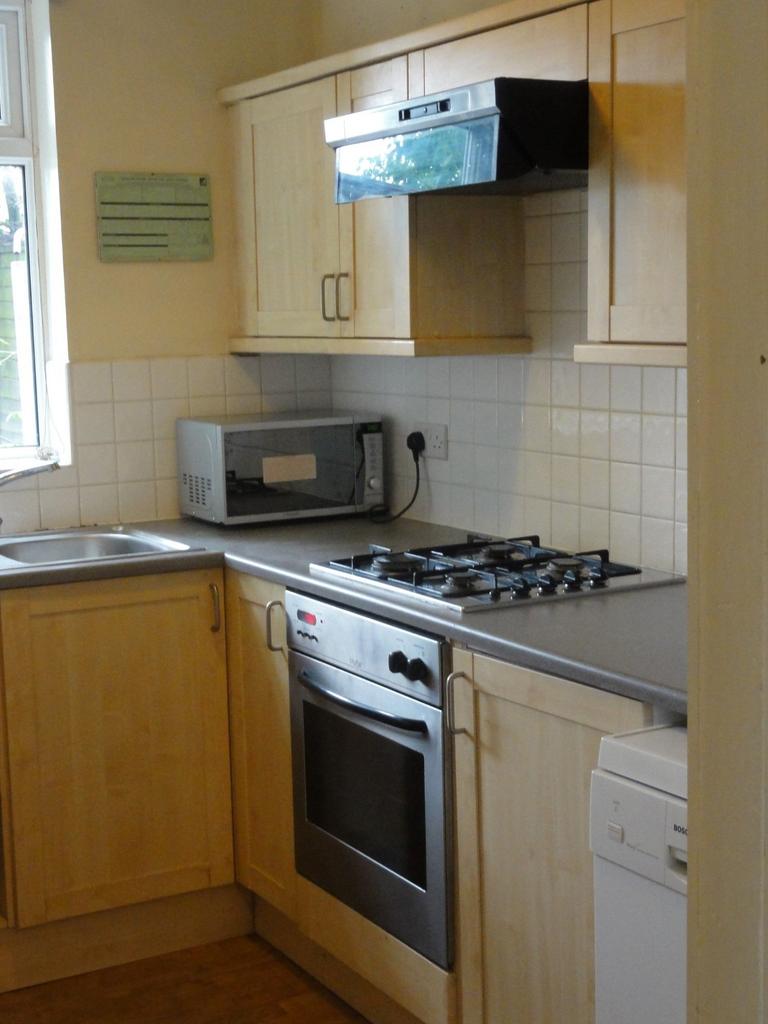 A compact kitchen featuring wooden cabinets, a ...