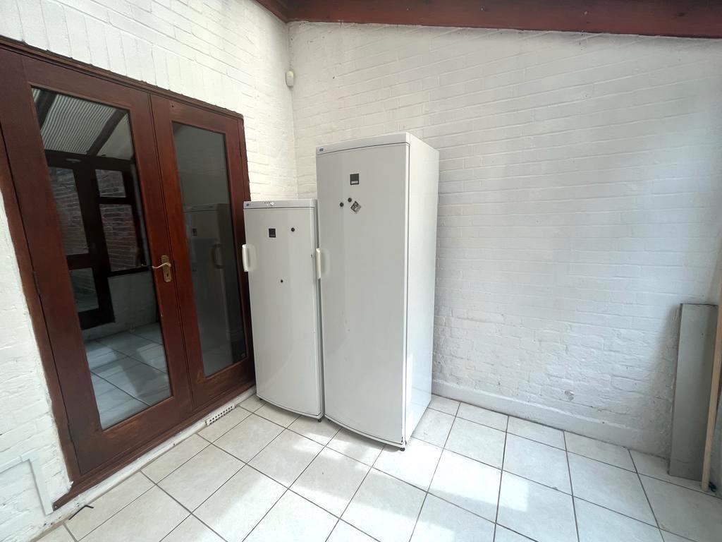 Bright tiled utility area with white-painted br...