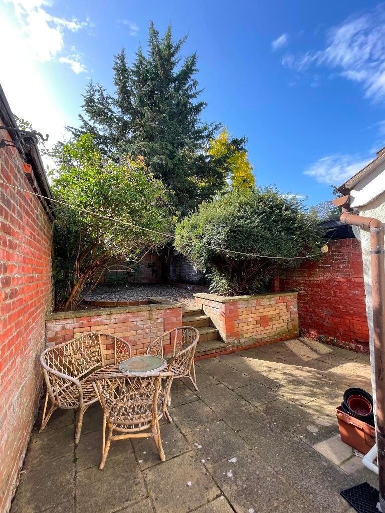 Sunny private courtyard with paved patio, matur...