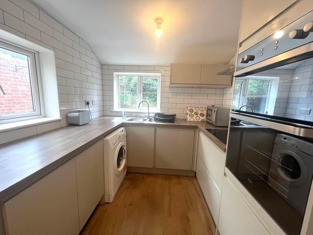 Bright, modern galley kitchen with light wood w...