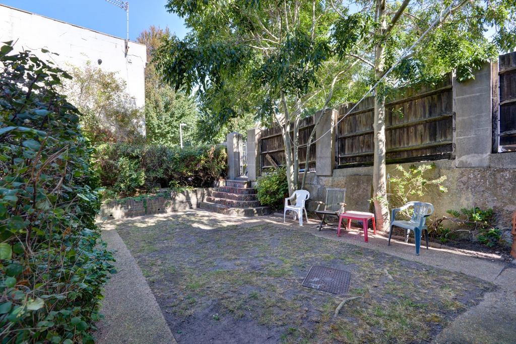 Private paved garden with mature trees and plan...
