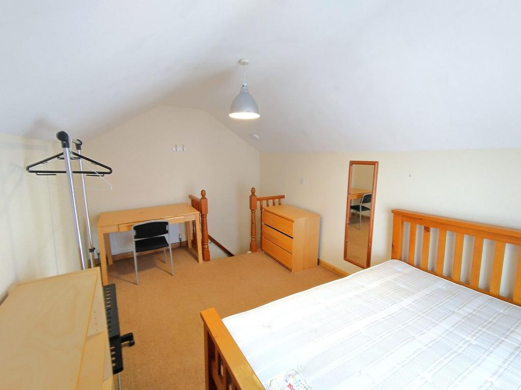 Bright attic double bedroom with wooden bed fra...