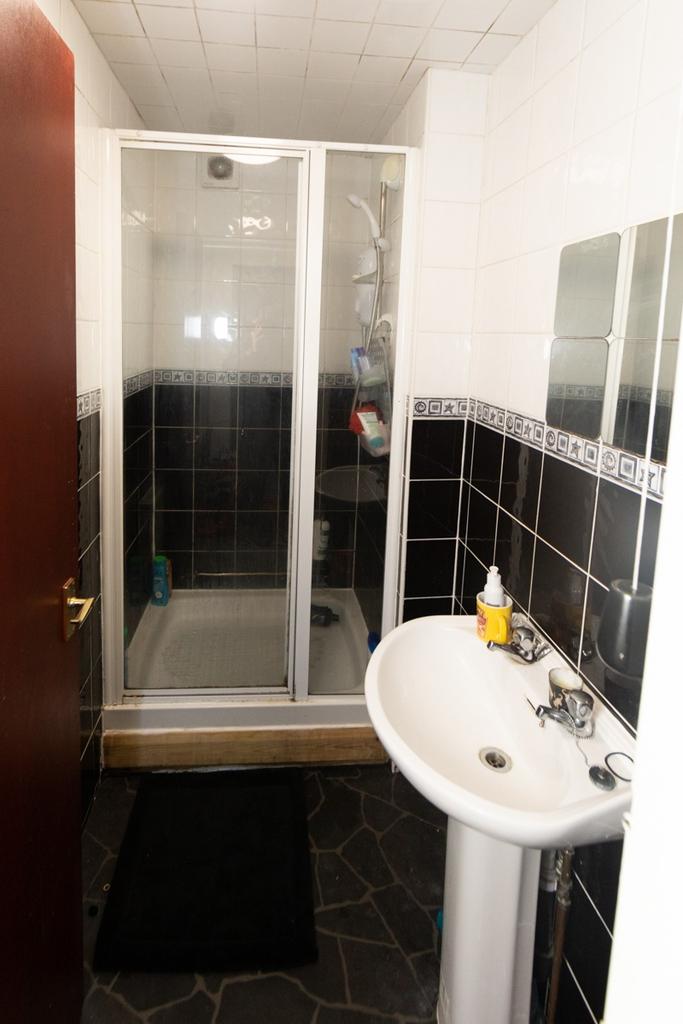 A compact bathroom featuring a small shower enc...