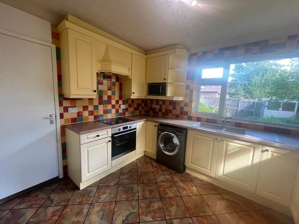 Bright, well-equipped kitchen with fitted cream...