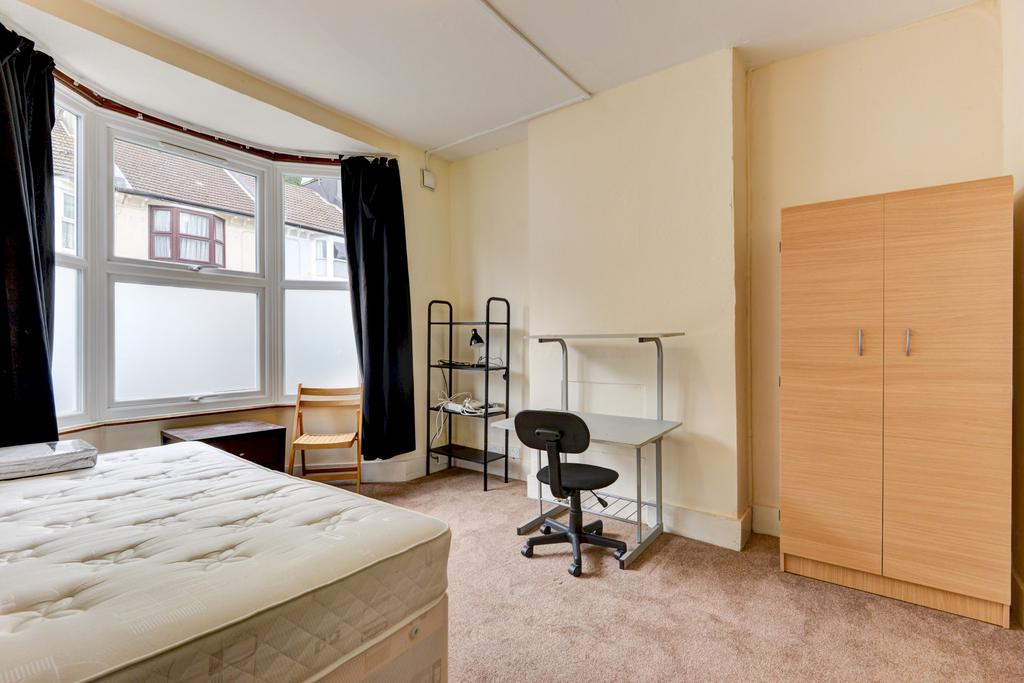 A bright and tidy bedroom featuring a large win...