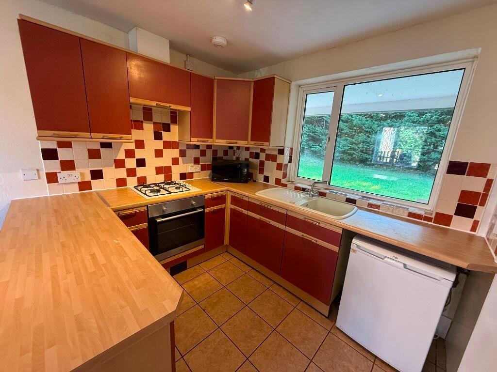 Well-lit fitted kitchen with warm wood-effect w...
