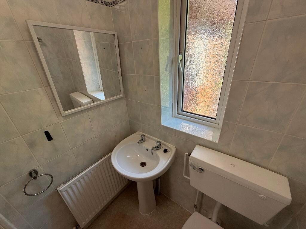 Neat tiled bathroom with a pedestal sink, frost...