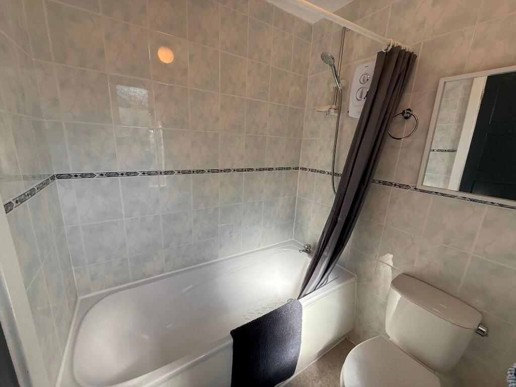 Bright, tiled bathroom featuring a full-size ba...