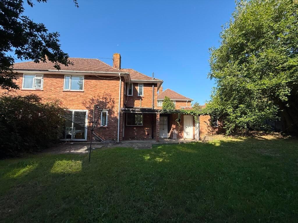Spacious rear garden with an open lawn, mature ...