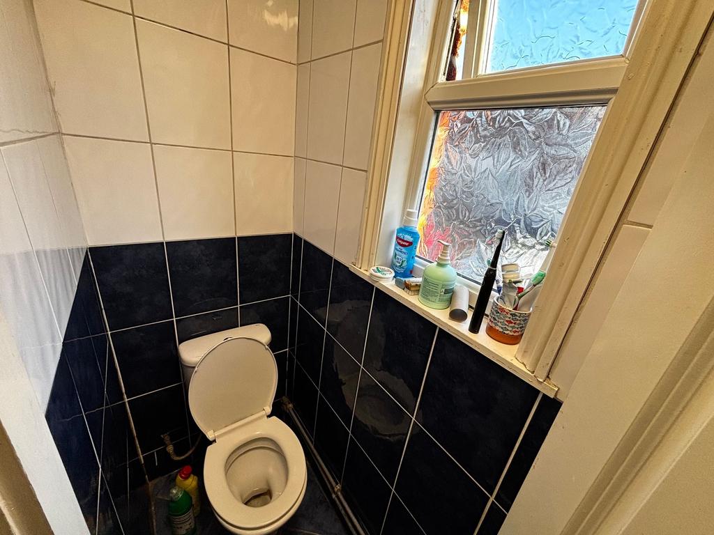 Compact tiled WC with a white toilet, frosted w...
