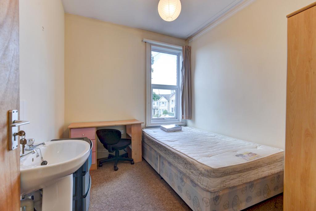 Compact bedroom with a single bed, built-in sin...