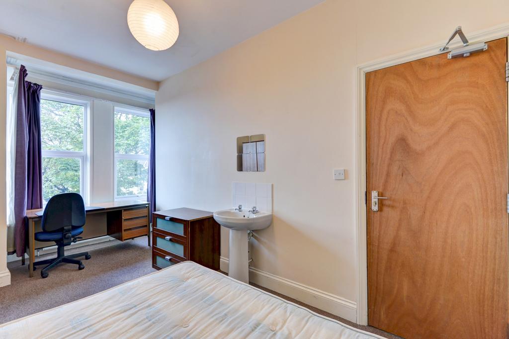 A cozy bedroom featuring a neatly made bed and ...