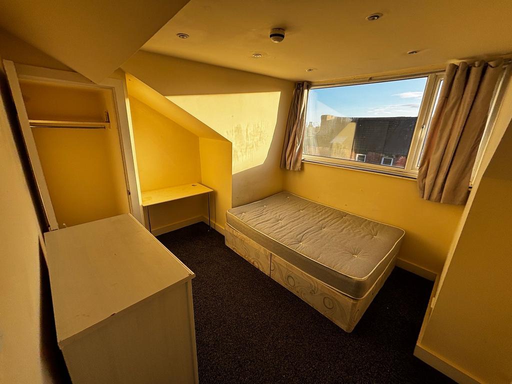 Bright single bedroom with a large window letti...