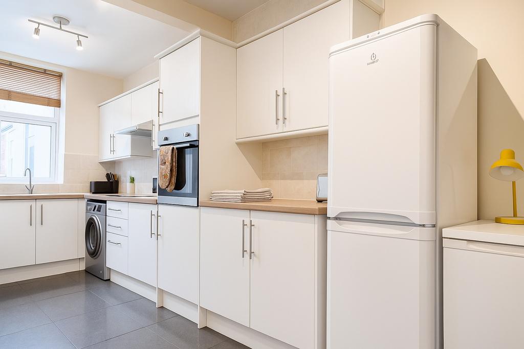 Bright, modern kitchen with white cabinetry, wo...