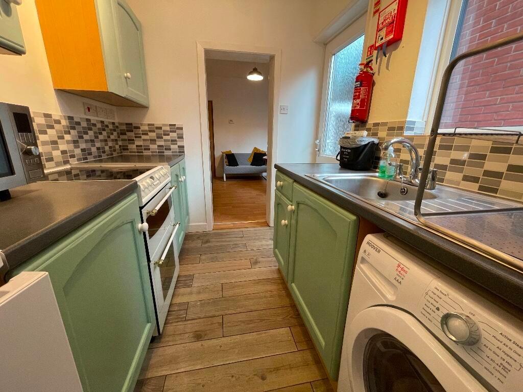 Bright galley kitchen with mint-green cabinets,...