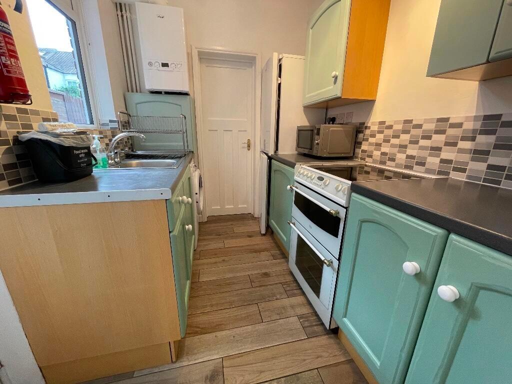 Bright galley kitchen with mint green cabinets,...