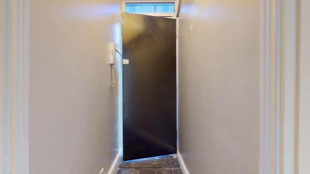 Narrow interior hallway with a dark door at the...