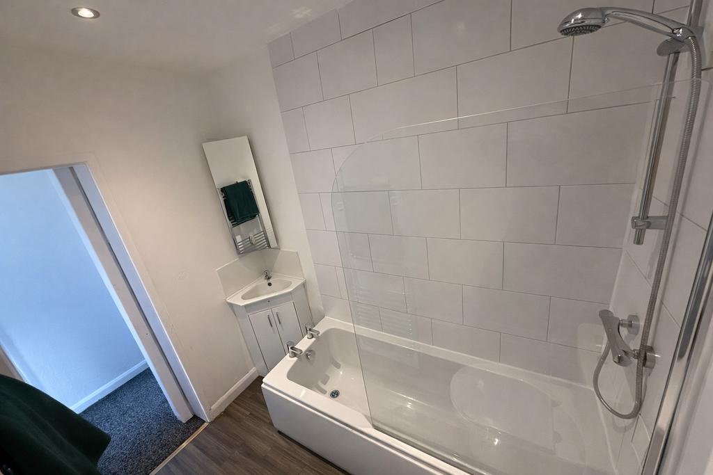 Bright, modern bathroom with a tiled bath and o...