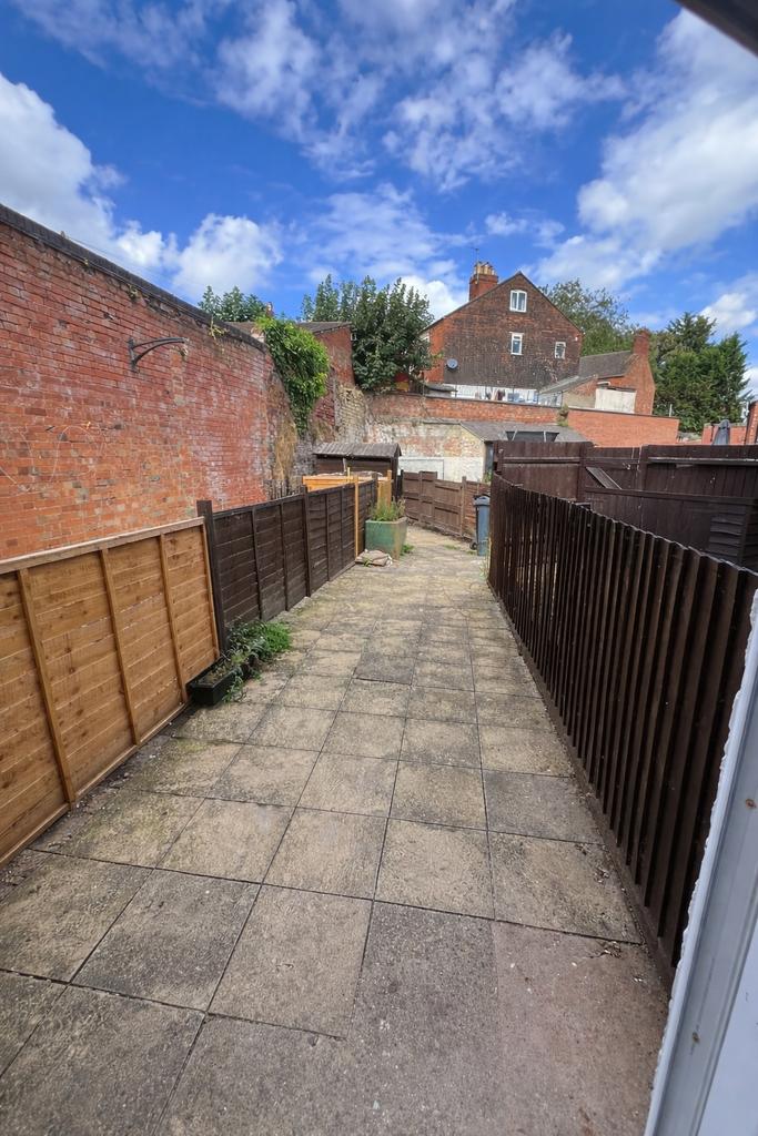 Long paved private garden with high brick walls...