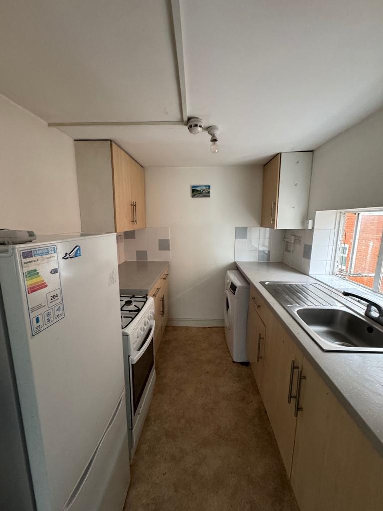 Narrow galley kitchen with light wood cabinets,...
