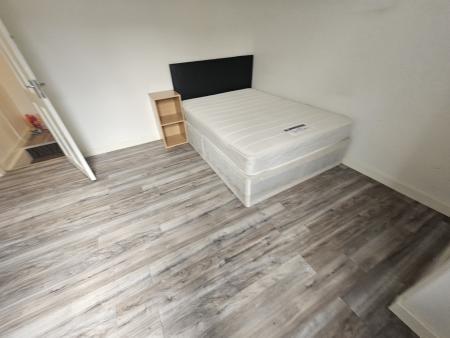 A tidy single bedroom with modern wood-effect f...