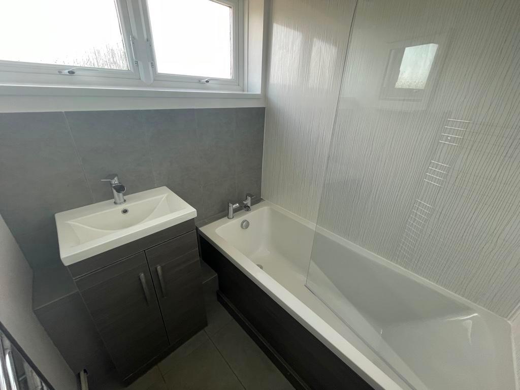 Bright, modern bathroom featuring a tiled bath ...