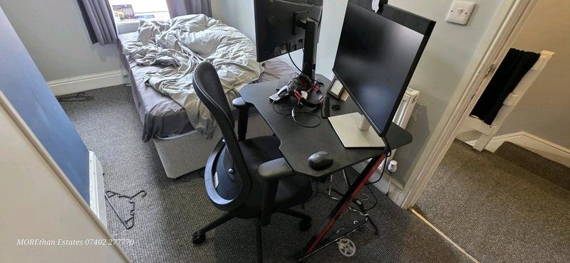 Compact bedroom with desk and dual monitors...