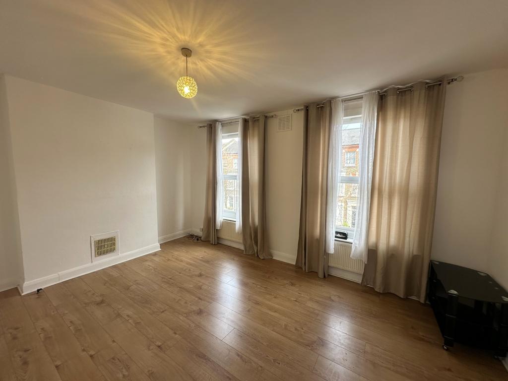 Bright living room with tall windows and woodfl...