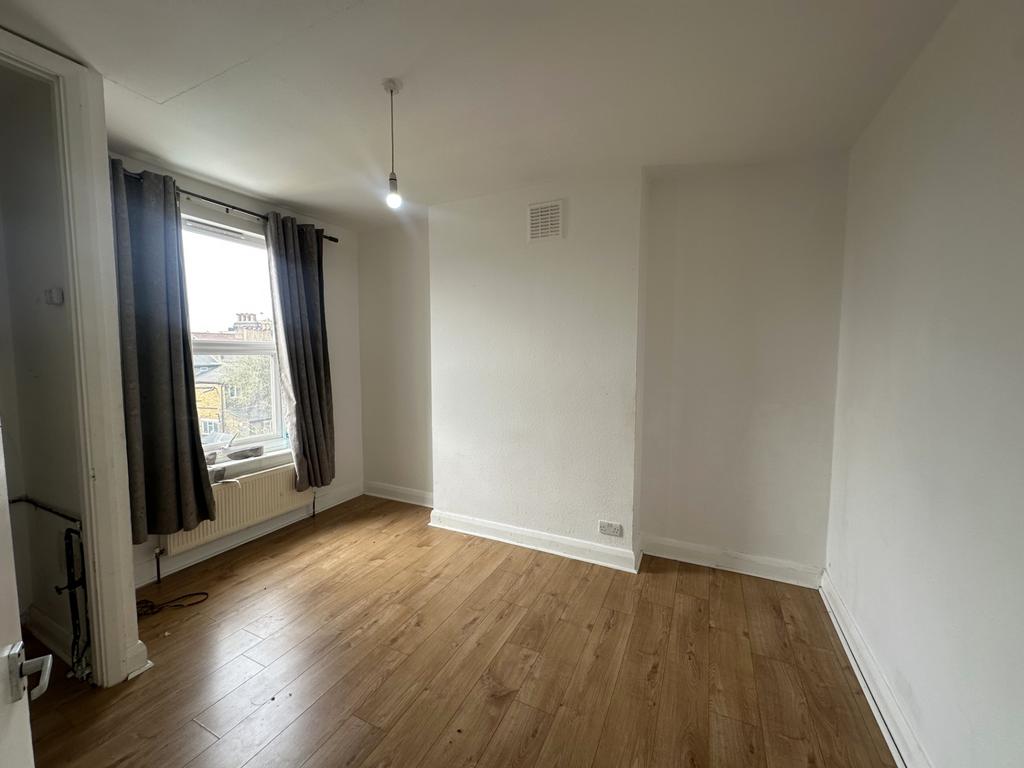 Bright bedroom with large window and wood floor...