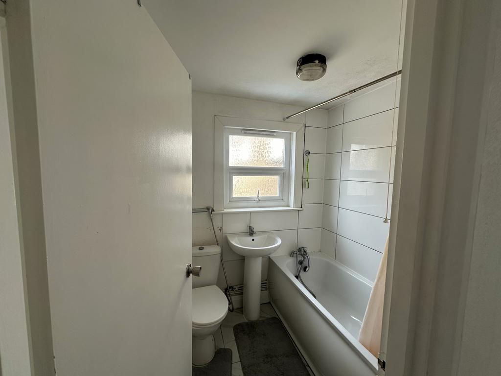Bright bathroom with white tiles and bath...