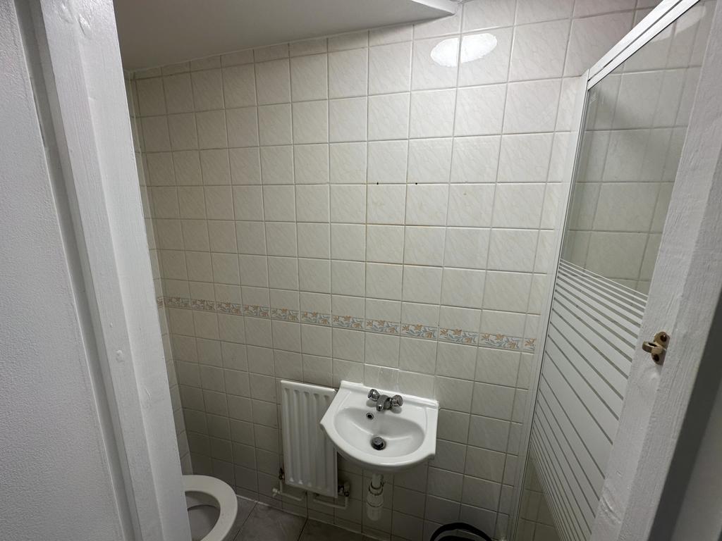 Compact bathroom with sink and tiled walls...