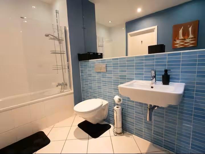 Modern bathroom with blue tiled half-wall, wall...