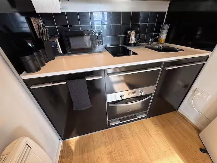 Modern fitted kitchenette with sleek black cabi...