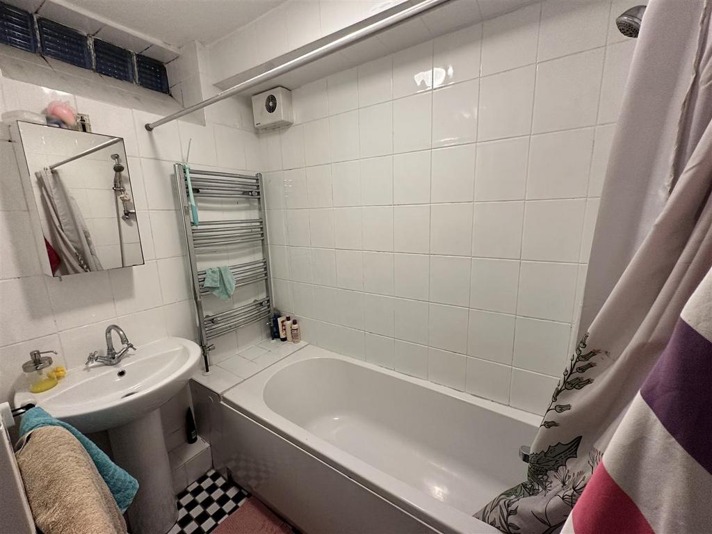 Bright tiled bathroom with bath and heated rail...