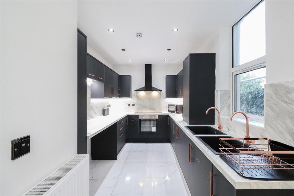 Modern galley kitchen with sleek dark cabinets,...