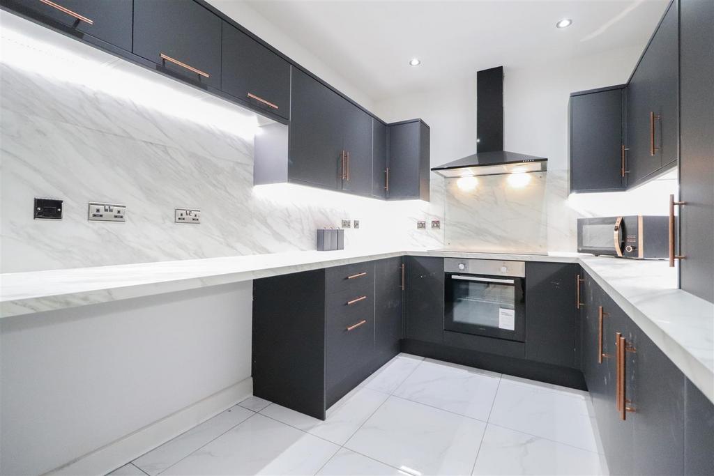 Modern U-shaped kitchen with sleek dark cabinet...