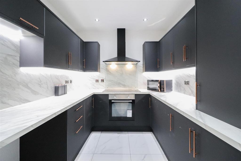 Modern galley kitchen with sleek dark cabinetry...